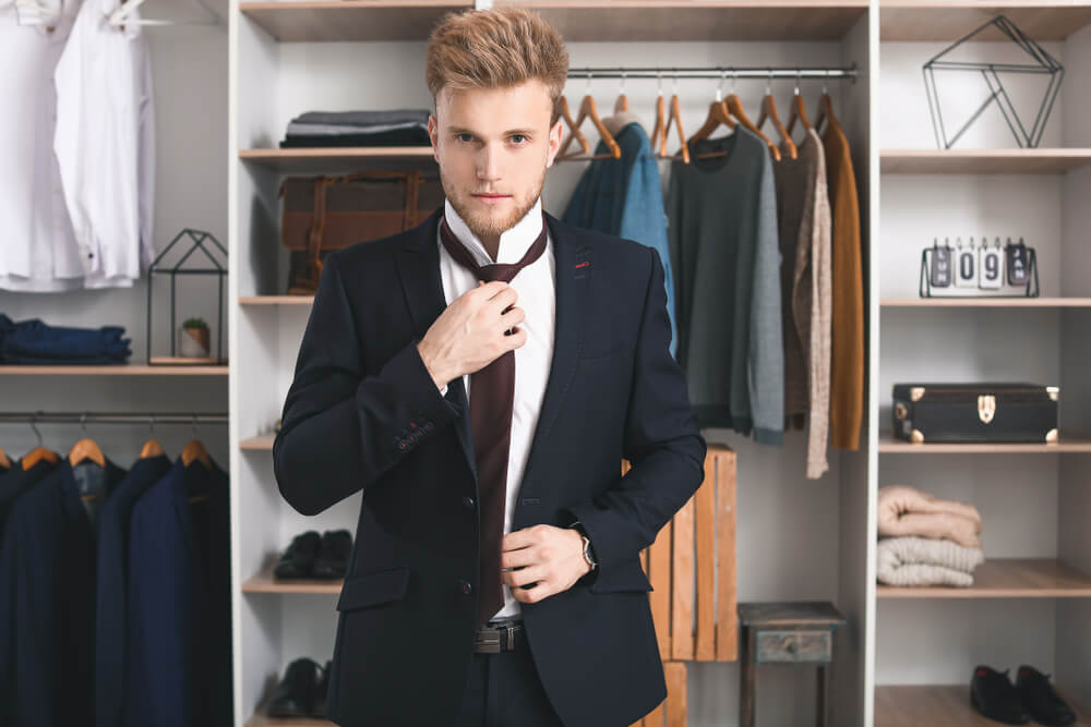 man trying a suit in front of his wardrobe