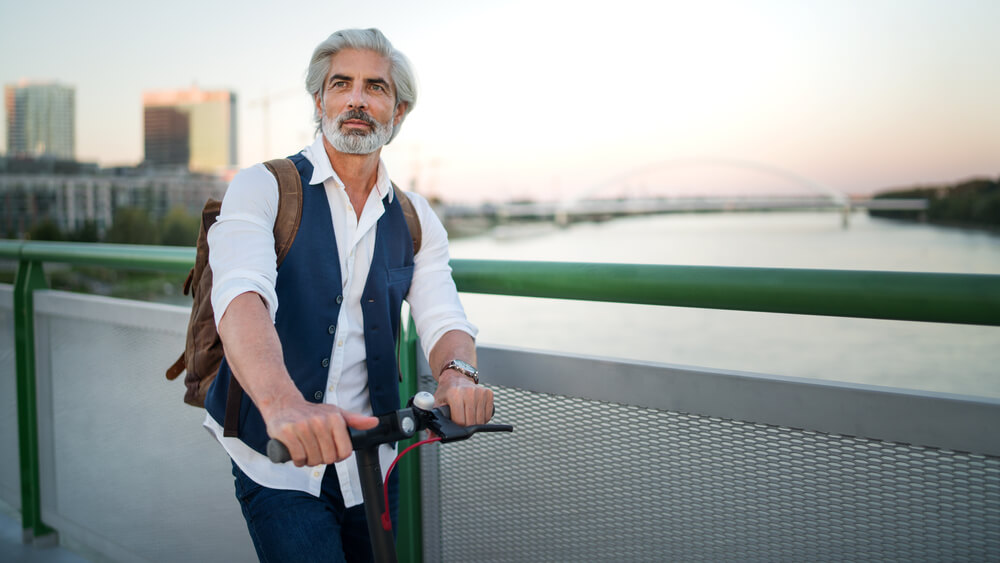 man wearing a waistcoat while holding a scooter