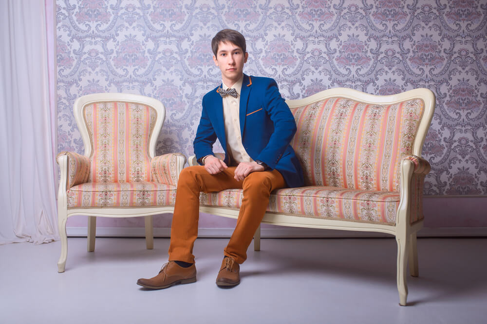 man wearing a suit with unbuttoned jacket sitting on a sofa