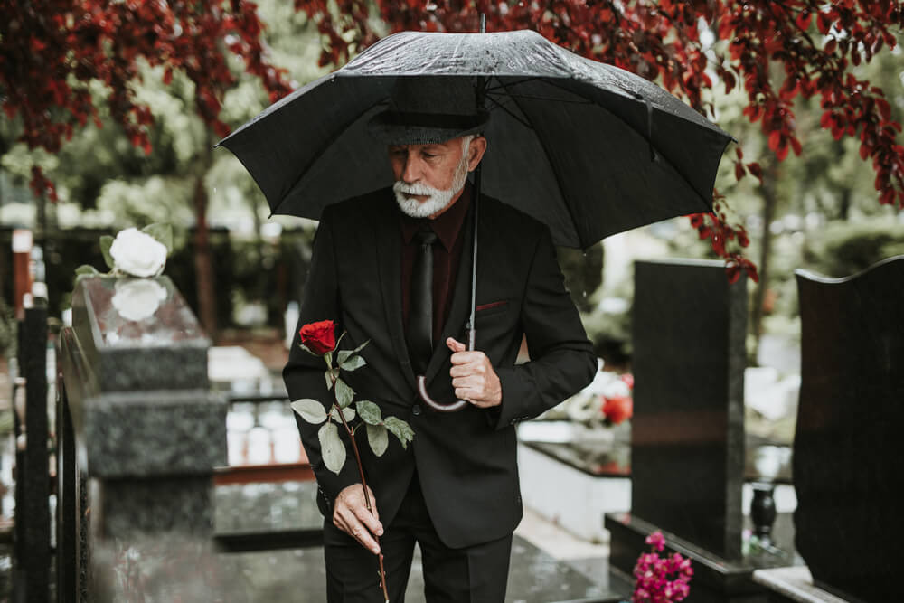 older man attending a funeral in a black suit