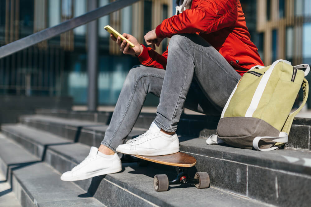 man wearing grey jeans with white trainers